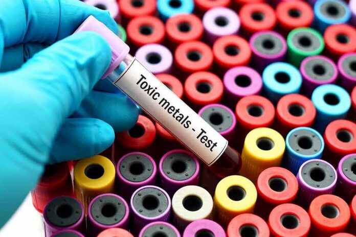 Gloved hand holding blood vial over colorful test tubes