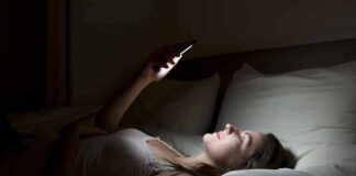 Woman lying in bed looking at smartphone