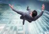 businessman falling between tall skyscrapers