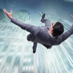 businessman falling between tall skyscrapers