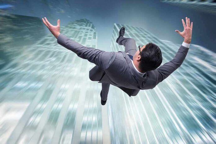 businessman falling between tall skyscrapers